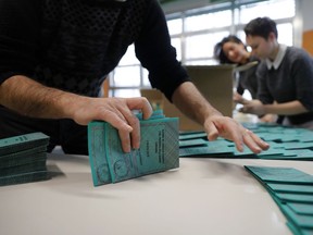 Polling station workers prepare ballots in Rozzano, near Milan, Italy, Saturday, March 3, 2018.