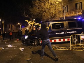 A man throws a metal barrier at a van of the Catalan Mossos d'Esquadra regional police blocking the way of pro-independence supporters trying to reach the Spanish government office in Barcelona, Spain, Sunday, March 25, 2018. Grassroots groups both for and against Catalan secession called for protests Sunday in Barcelona after Carles Puigdemont, the fugitive ex-leader of Catalonia and ardent separatist, was arrested Sunday by German police on an international warrant.