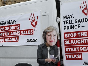 A protester wears a mask of Britain's Prime Minister Theresa May outside the Palace of Westminster in London, Wednesday, March 7, 2018, to demonstrate against Britain's role as an arms supplier to Saudi Arabia, and to protest against the war in Yemen. Saudia Arabia's crown prince is beginning a visit to Britain, where he will be greeted by Queen Elizabeth II -- and met by protesters against the war in Yemen.
