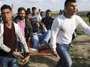 Palestinian protesters evacuate a wounded person during clashes with Israeli troops on the Israeli border with Gaza, east of Gaza City, Friday, March 16, 2018.