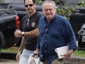 A federal police officer escorts Brazil's former Agriculture Minister Wagner Rossi into Federal Police headquarters in Sao Paulo, Brazil, Thursday, March 29, 2018. Rossi has been arrested in connection to an investigation into whether President Michel Temer accepted bribes for favors to a company operating at the country's largest port.