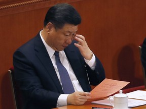 Chinese President Xi Jinping looks at a ballot for an amendment to China's constitution that will abolish term limits on the presidency and enable him to rule indefinitely, during a plenary session of the National People's Congress at the Great Hall of the People in Beijing, Sunday, March 11, 2018.