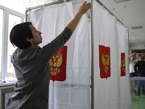 A polling station official prepares vote cabins for the 2018 Russian presidential election at a polling station in Simferopol, Crimea, Saturday, March 17, 2018. Russian voters, observers and eight presidential candidates are gearing up for an election that will undoubtedly hand Vladimir Putin another six-year term. (AP Photo)