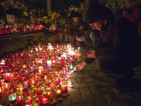 People light candles by a floral tribute for the victims of a fire in a multi-story shopping center in the Siberian city of Kemerovo, about 3,000 kilometers (1,900 miles) east of Moscow, Russia, Monday, March 26, 2018. Russian officials say that fire escapes were blocked and a PA system was turned off during a fire at a shopping mall in a Siberian city that killed over 50 people. Witnesses reported no alarms and no staff to help them leave the Winter Cherry mall in Kemerovo.