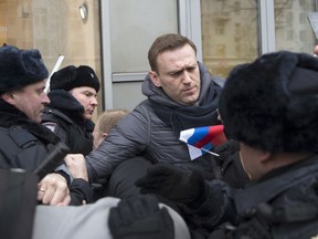 FILE - In this Sunday, Jan. 28, 2018 file phot, Russian opposition leader Alexei Navalny, center, is detained by police officers in Moscow, Russia. Navalny, the most vocal Putin critic, was barred from joining the presidential campaign due to a criminal conviction widely seen as a political punishment for his opposition activities and called for boycotting the vote. President Vladimir Putin seems self-assured and confident of victory in the election on Sunday, March 18, even as the Kremlin works hard to bolster turnout to make the result as impressive as possible.
