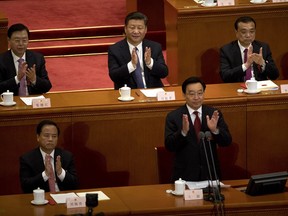 In this Sunday, March 11, 2018, photo, Chinese President Xi Jinping, top center, applauds after hearing the results of a vote on a constitutional amendment during a plenary session of China's National People's Congress (NPC) at the Great Hall of the People in Beijing. China's move to scrap term limits and allow Xi to serve as president indefinitely puts him on track to deal with some of the country's weightiest long-term sovereignty challenges, especially the fates of Hong Kong and Taiwan.