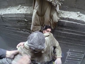 This frame grab from video released on Thursday, March. 1, 2018 by the Syrian Civil Defense White Helmets, which has been authenticated based on its contents and other AP reporting, shows members of the Syrian Civil Defense group rescuing a man from the basement of a building following strikes in the eastern Ghouta region near Damascus, Syria. Thousands of residents are huddling underground in basements and tunnels, hiding from the horror raining down from Syrian army jets that almost never leave the skies. Residents of the rebel-held suburbs east of Damascus describe damp, mostly unhygienic living conditions underground, and moments of pure terror when bombs fall above their heads, fearing their shelters would collapse. (Syrian Civil Defense White Helmets via AP)