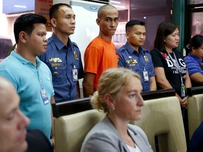 U.S. Embassy Assistant Attache and Homeland Security Investigator Jim Anglemeyer, left, and Norway's Vest Police District's Assistant Police Chief Sidsel Isachsen sit with National Bureau of Investigation and police officers as they present an arrested cybersex suspect named as Anselmo Ico, third from left standing, Friday, March 9, 2018 in Manila, Philippines. Officials say Norwegian and U.S. authorities have helped the Philippines capture Ico who allegedly exploited children into joining sex shows with him then showing the lewd video online to paying foreign clients.