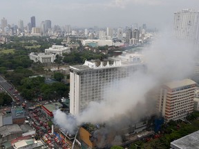 Firemen battle a fire that engulfs the Manila Pavilion Hotel and Casino Sunday, March 18, 2018 in Manila, Philippines. A fire hit the hotel, where more than 300 guests were evacuated, some by helicopter, an official said.