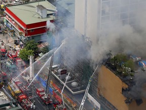 Firemen battle a fire that engulfs the Manila Pavilion Hotel and Casino Sunday, March 18, 2018 in Manila, Philippines. A fire hit the hotel, where more than 300 guests were evacuated, some by helicopter.
