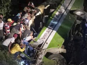 In this Tuesday, March 20, 2018, photo provided by Provincial Disaster Risk Reduction Management Office (PDRRMO), Mindoro Occidental, rescuers and volunteers try to rescue trapped passengers from the wreckage of the passenger bus after it careened off a road and fell into a ravine at Sablayan township, Mindoro Occidental province in central Philippines, south of Manila. The crash occurred Tuesday night as the bus was heading on a downhill stretch of road, killing more than a dozen of passengers. (PDRRMO, Mindoro Occidental via AP)