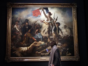 A woman watches "La liberte guidant le peuple" by Eugene Delacroix at the Louvre museum, in Paris, Tuesday, March 27, 2018. The Louvre is seeking to reinterpret the work of Eugene Delacroix in a retrospective that goes beyond the brief years in which he painted his most recognizable masterpieces such as "Liberty Leading the People" that's graced postage stamps and bank notes in France as well as a Coldplay album cover. The exhibition runs from March 29 to July 23, 2018.