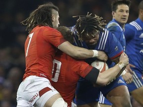 France's Mathieu Bastareaud , centre, is grabbed by Wales' Josh Navidi, left, and Wales' Dan Biggar during the Six Nations rugby union match between Wales and France at the Millennium stadium in Cardiff, Wales, Saturday, March 17, 2018.