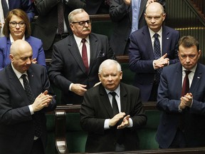 Poland's powerful ruling party leader Jaroslaw Kaczynski, center, and some government members applaud a parliament resolution in parliament in Warsaw, Poland, Tuesday, March 6, 2018. Poland's lawmakers have approved a resolution marking mass anti-communist protests that occurred 50 years ago and condemning an anti-Semitic purge that ensued.