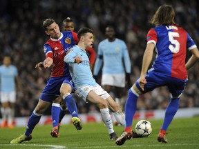 Basel's Fabian Frei, left, challenges for the ball with Manchester City's Phil Foden, center, during the Champions League, round of 16, second leg soccer match between Manchester City and Basel at the Etihad Stadium in Manchester, England, Wednesday, March 7, 2018.