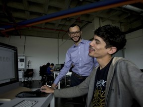 In this March 7, 2018 photo, Gabriel Jimenez, behind, jokes with one of his employees at the office of his company "The Social Us" in Caracas, Venezuela. Jimenez, 27, was catapulted to something of tech stardom in Venezuela last month when he stood alongside President Nicolas Maduro and two Russian businessmen on national TV signing a contract to position the petro, as the fledgling cryptocurrency is known, among international investors.