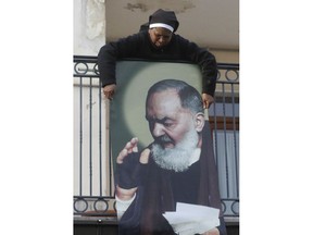 A nun exposes a poster portraying St. Padre Pio on a balcony in San Giovanni Rotondo, Southern Italy, Friday, March 16, 2018. Pope Francis is making a pastoral visit to the places where Padre Pio was born and lived Saturday.