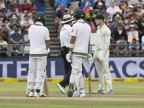 Cameron Bancroft of Australia, left, is questioned by umpires regarding ball tampering on the third day of the third cricket test between South Africa and Australia at Newlands Stadium, in Cape Town, South Africa, Saturday, March 24, 2018. Australia cricketers confessed to ball tampering in a desperate plot hatched by the team's leaders as they saw the match slipping away. Batsman Cameron Bancroft was tasked with carrying out the tampering by using yellow adhesive tape to pick up "granules" beside the pitch and rub it on the ball to rough it up in an attempt to get it to reverse swing at Newlands.