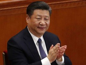 In this Sunday, March 11, 2018, photo, Chinese President Xi Jinping applauds after hearing the results of a vote on a constitutional amendment during a plenary session of China's National People's Congress (NPC) at the Great Hall of the People in Beijing.