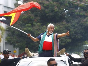 East Timorese independence hero Xanana Gusmao, center, waves a national flag upon arrival in Dili, East Timor, Sunday, March 11, 2018. East Timorese lined the road to the capital's international airport to cheer for Gusmao for leading negotiations that settled the sea border between the impoverished country and Australia.