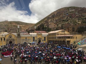 In this photo made through an aerial cable car window, residents attend an outdoor Mass after taking part in a procession honoring their patron saint, Our Lady of Socavon, in Oruro, Bolivia, Thursday, March 1, 2018. Hundreds, including Oruro's archbishop, governor and mayor, marched in protest of a Bolivian artist and her painting that depicts the religious icon wearing red lingerie and transparent stockings. The governor gave state workers the day off in order to participate in the demonstration.