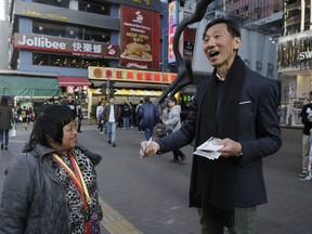 Hong Kong pro-democracy by-election candidate Edward Yiu, right, delivers his promotional leaflets during an election campaign in Hong Kong, Saturday, March 10, 2018. Residents of the semiautonomous Chinese city are set to head to the polls on Sunday in a election in which pro-democracy supporters hope to reclaim lost ground after authorities disqualified lawmakers or candidates.