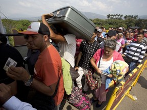 FILE - In this Feb. 21, 2018 file photo, Venezuelans cross the International Simon Bolivar bridge into Cucuta, Colombia, as rising numbers of Venezuelans are fleeing in a burgeoning refugee crisis that could soon match the flight of Syrians from the war-torn Middle East. The Trump administration is providing $2.5 million in emergency food and medicine to Venezuelan migrants in Colombia in the U.S.' first action to alleviate a burgeoning humanitarian crisis that has reverberated across Latin America, according to a USAID statement on Tuesday, March 20, 2018.