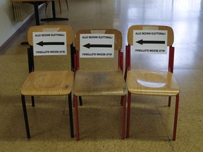 Signs on three chairs read in Italian "to the polling", at a polling station in Milan, Italy, Sunday, March 4, 2018. More than 46 million Italians were voting Sunday in a general election that is being closely watched to determine if Italy would succumb to the populist, anti-establishment and far-right sentiment that has swept through much of Europe in recent years.