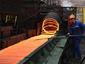 In this March 5, 2018 photo, a worker manipulates coils of steel at Xiwang Special Steel in Zouping County in eastern China's Shandong province. China says it "firmly opposes" U.S. President Donald Trump's tariff increase for imported steel and aluminum but gave no indication whether Beijing might impose its own measures in response. (Chinatopix via AP)