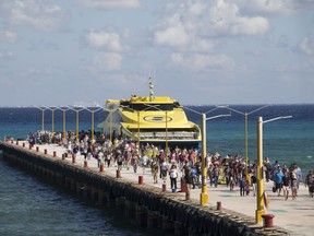 In this Friday, March 2, 2018 photo, tourists and passengers disembark from a ferry on to the wharf on Playa del Carmen, Mexico. In a notice posted Friday, March 9,  on its website, the U.S. Embassy in Mexico has narrowed its travel warning for the Caribbean resort city of Playa del Carmen amid what it calls an unspecified "ongoing security threat" just as the spring holiday season is kicking into high gear.