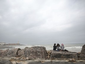 In this Wednesday, March 7, 2018 photo, women observe waves on a stormy day by the beach in Rabat, Morocco. Morocco's Parliament passed a long-sought law last month on combating violence against women. It recognizes some forms of abuse for the first time and criminalizes some forms of domestic violence. But critics say it doesn't go nearly far enough to address the deep-seated problem.