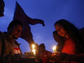 Nepalese people light candles to pay tribute to those who died in Monday's plane crash in Kathmandu, Nepal, Tuesday, March 13, 2018.