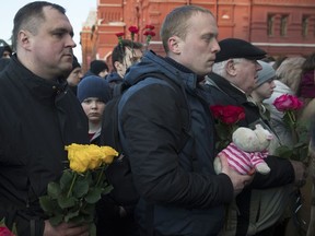 People bring flowers and toys during a day of mourning for the victims of Sunday's fire in a shopping mall in the Siberian city of Kemerovo, in Manezhnaya square, near Kremlin in Moscow, Russia, Wednesday, March 28, 2018.