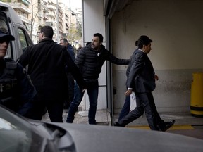 Greek police officers in plain clothes escort two of the eight Turkish servicemen, right, to the appeal court in Athens, on Friday March 16, 2018. The servicemen fled to Greece in a helicopter and requested political asylum. Athens appeal judges will hear new Turkish extradition request for military officers, accused of participation in anti-Erdogan coup.