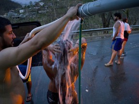 FILE - In this Sept. 28, 2017 file photo, people affected by Hurricane Maria bathe in water piped from a creek in the mountains, in Naranjito, Puerto Rico. In the six months since the hurricane, more than 135,000 people have fled to the U.S. mainland, according to a recent estimate by the Center for Puerto Rican Studies at Hunter College in New York.
