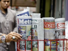 A man takes a copy of newspaper at a grocery shop in Shah Alam, Malaysia, Monday, March 26, 2018. Malaysia's government on Monday proposed new legislation to outlaw fake news with a 10-year jail term for offenders, in a move slammed by critics as a draconian bid to crack down on dissent ahead of a general election. Prime Minister Najib Razak has been dogged by a multibillion-dollar corruption scandal involving an indebted state fund, and rights activists fear the new law could be used to criminalize reports on government misconduct and critical opinions.