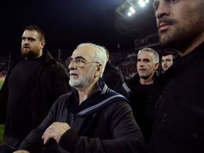FILE - In this Sunday, March 11, 2018 file photo, PAOK owner, businessman Ivan Savvidis, center, walks on the pitch escorted by his bodyguards during a Greek League soccer match between PAOK and AEK Athens in the northern Greek city of Thessaloniki.  Savvidis was banned for three years on Thursday, March 29, 2018, for his part in violence during a match against AEK Athens, including running onto the field with a holstered pistol on his hip.