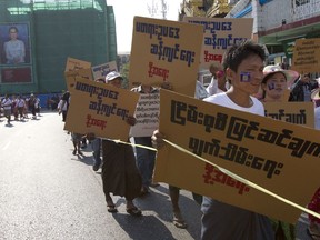 Demonstrators march to protest against a toughening Myanmar public assembly law in Yangon, Myanmar, Monday, March 5, 2018. About 200 demonstrators marched against the government's plans to amend the Peaceful Assembly and Peaceful Procession Law, a law governing public protests in a manner making it easier to charge protesters with crimes while increasing the penalties for violations. The portrait seen in the background is Myanmar leader Aung San Suu Kyi who led the civilian government proposed adding a clause that is punishable by a maximum three years imprisonment or fines. The placards read: "Stop amending the Peaceful Assembly and Peaceful Procession Law to the unfair law."