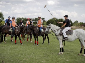 In this Feb. 27, 2018 photo, Stephane Buton, a polo instructor from France, right, teaches tourists how to swing the mallet at La Carona club, Capilla del Senor, Buenos Aires province, Argentina. Polo has traditionally been an exclusive, glamorous sport reserved for the rich elite. Argentina, with its wide plains and its rich culture of horseback riding among the Argentine cowboys known as Gauchos, is one of the dominating polo world powers.