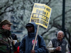 A man holds placards during an anti-war protest after U.S. President Donald Trump launched airstrikes in Syria, April 15, 2018 in New York City.