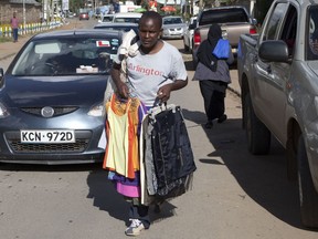 In this Saturday, April 7, 2018 photo, a man selling second hand clothes walks on street in Nairobi, Kenya. The used clothes cast off by Americans and sold in bulk in African nations, a multimillion-dollar business, have been blamed in part for undermining local textile industries.