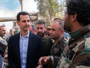 Syrian President Bashar al-Assad (C) talking with government troops in Eastern Ghouta, in a photo released March 18, 2018.