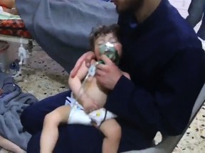 An image grab taken from a video released by the Syrian civil defence in Douma shows an unidentified volunteer holding an oxygen mask over a child's face at a hospital following a reported chemical attack on the rebel-held town on April 8, 2018.