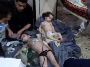 An image grab taken from a video released by the Syrian civil defence in Douma shows unidentified volunteers giving aid to children at a hospital following a reported chemical attack on the rebel-held town on April 8, 2018.