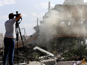 A journalist films the wreckage of a building described as part of the Scientific Studies and Research Centre (SSRC) compound in the Barzeh district, north of Damascus, during a press tour organised by the Syrian information ministry, on April 14, 2018. The United States, Britain and France launched strikes against Syrian President Bashar al-Assad's regime early on April 14 in response to an alleged chemical weapons attack after mulling military action for nearly a week. Syrian state news agency SANA reported several missiles hit a research centre in Barzeh, north of Damascus, "destroying a building that included scientific labs and a training centre".