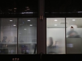 In this file photo taken on March 23, 2018 people are seen through blinds searching inside the offices of Cambridge Analytica in central London, just hours after a judge approved a search warrant of the offices.