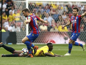 Crystal Palace's James McArthur, left and teammate Yohan Cabaye, right, battle for the ball with Watford's Abdoulaye Doucoure , during the English Premier League soccer match between Watford and Crystal Palace, at Vicarage Road, in Watford, England,  Saturday April 21, 2018.