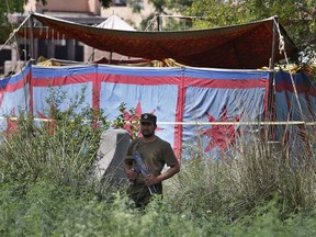 A Pakistani police officer stands guard near a grave, covered with tent,  of Sana Cheema, an Italian woman of Pakistani origin, who was allegedly killed by her family members, in the neighborhood of Mangowal, near Gujrat, Pakistan, Wednesday, April 25, 2018. Pakistani police arrested the father and the uncle suspected in an "honor" killing of a 25-year-old Italian citizen, a woman of Pakistani origin who refused to marry the man they chose for her, a police officer said.