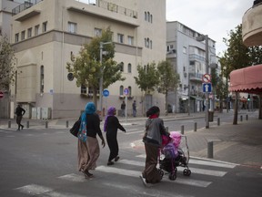 In this Tuesday, April 3, 2018 photo, African Migrants cross a street in southern in Tel Aviv, Israel. After years of uncertainty, African migrants living in Israel felt hope when Israel's prime minister announced a deal to resettle many of them in Western countries. But hours later, Prime Minister Benjamin Netanyahu backtracked. African migrants living in the slums of southern Tel Aviv accuse the Israeli leader of playing politics with their lives and say Israel must find a solution to their plight.