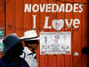 Election campaign posters hang ahead of tomorrow's elections at Mercado 4 where men wait for a bus in Asuncion, Paraguay, Saturday, April 21, 2018. Paraguay holds general elections on Sunday, April 22.